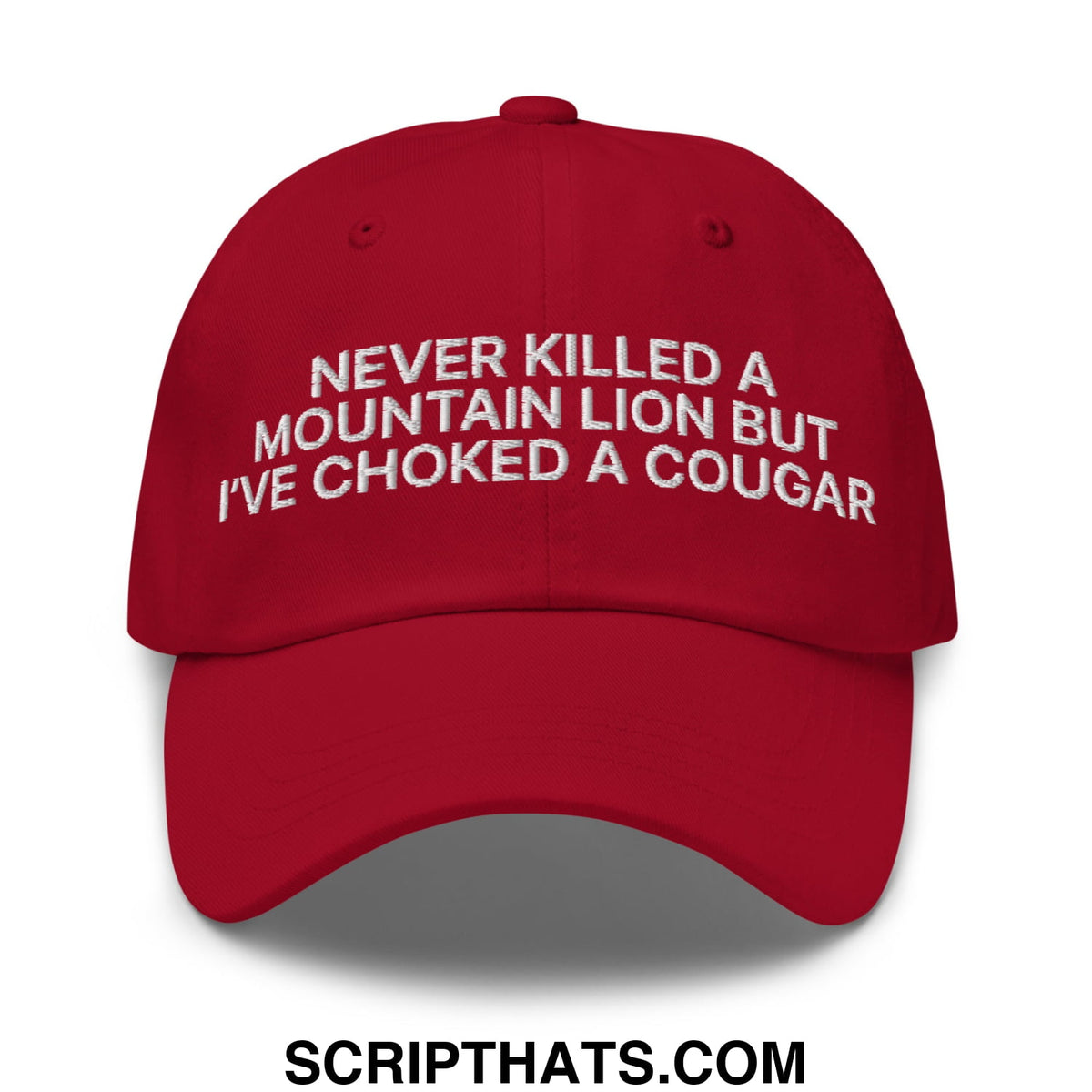 A vibrant red unstructured dad hat with white embroidered text reading never killed a mountain lion but ive choked a cougar