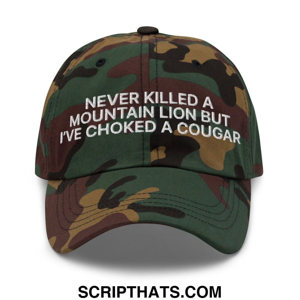 A camouflage-patterned unstructured dad hat with white embroidered text never killed a mountain lion but ive choked a cougar