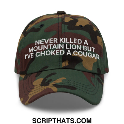 A camouflage-patterned unstructured dad hat with white embroidered text never killed a mountain lion but ive choked a cougar