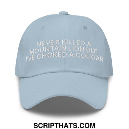 Light blue unstructured dad hat with white embroidered text never killed a mountain lion but ive choked a cougar