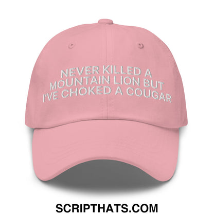 A soft pink unstructured dad hat with silver embroidered text never killed a mountain lion but ive choked a cougar