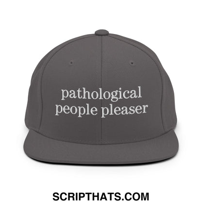 A dark gray flat bill brim snapback hat with white embroidered text reading pathological people pleaser