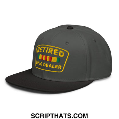 Dark gray snapback hat with yellow embroidered retired drug dealer patch and rastafarian-colored stripes