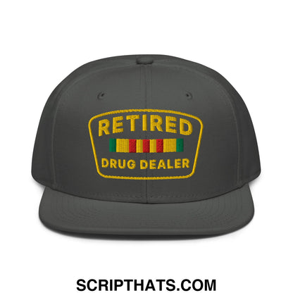 Dark gray snapback cap with yellow embroidered retired drug dealer patch and colorful striped ribbons on flat bill
