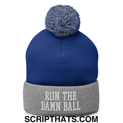 Royal blue knit beanie with gray cuffed brim and pom pom featuring white embroidered text run the damn ball