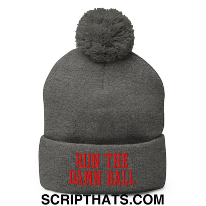 Gray knit beanie with a fuzzy pom pom and red embroidered run the damn ball text on the cuff