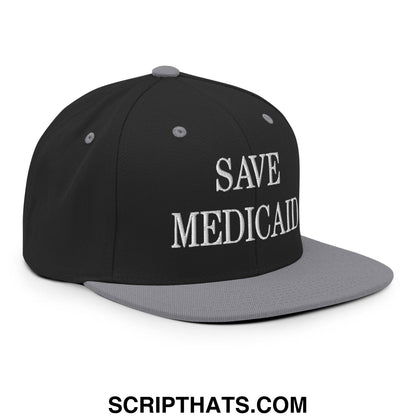 Black and gray snapback hat with save Medicaid embroidered in white on the flat brim bill