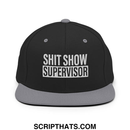 Black snapback hat with gray flat bill brim and embroidered white shit show supervisor text on front
