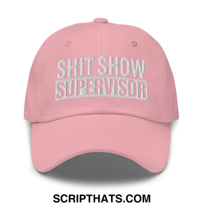 A soft pink unstructured dad hat with shit show supervisor embroidered in white thread on the front