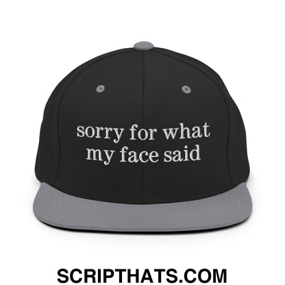 Black snapback cap with gray flat bill brim and white embroidered sorry for what my face said text