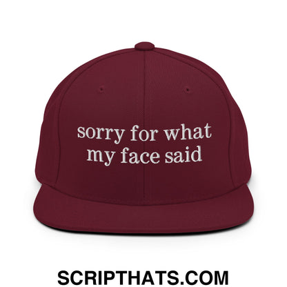 Maroon snapback hat with white embroidered sorry for what my face said text and flat bill brim design