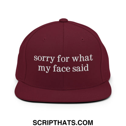 Maroon snapback hat with white embroidered sorry for what my face said text and flat bill brim design