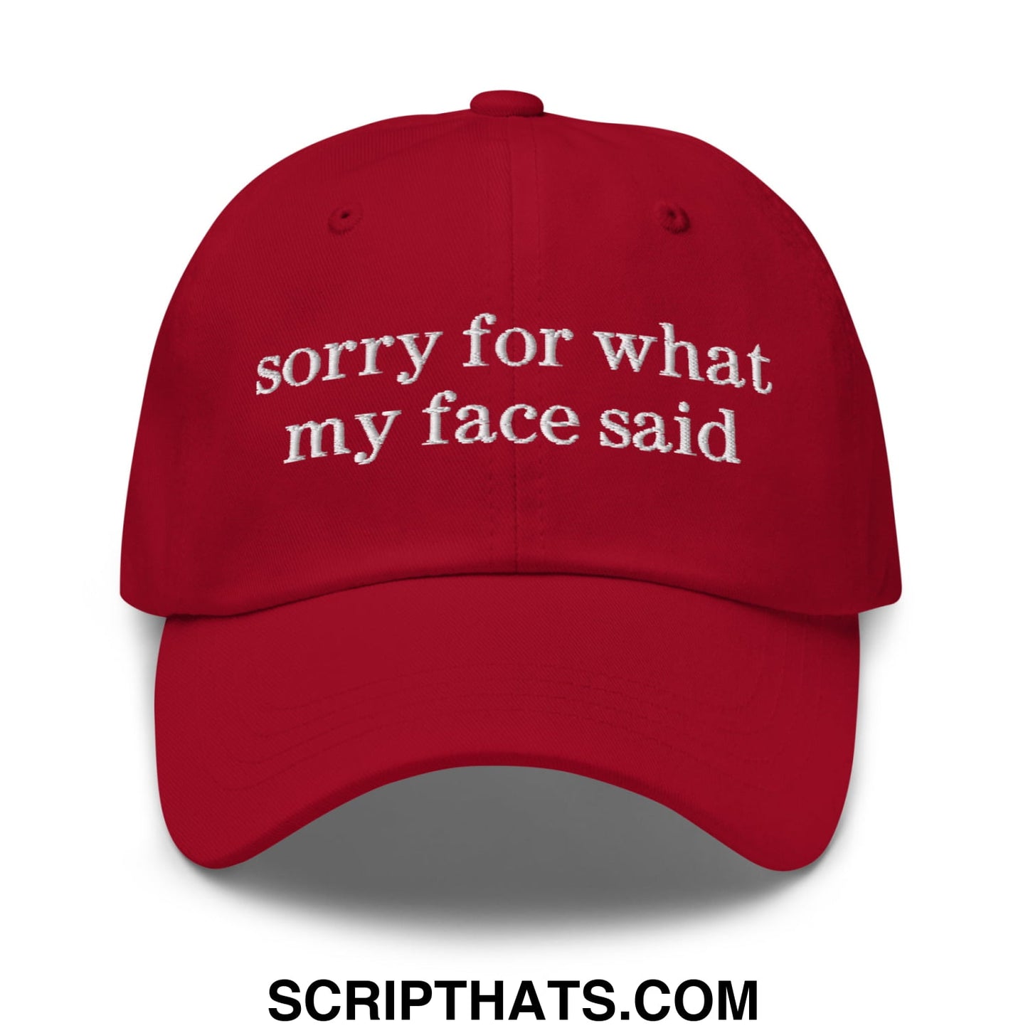 A vibrant red unstructured dad hat with white embroidered sorry for what my face said text on the front