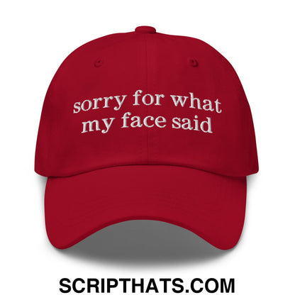 A vibrant red unstructured dad hat with white embroidered sorry for what my face said text on the front