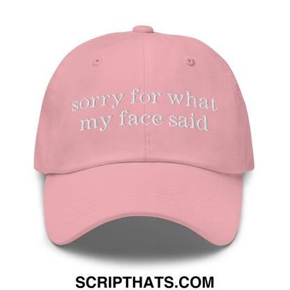 A soft pink unstructured dad hat with white embroidered text sorry for what my face said on the front