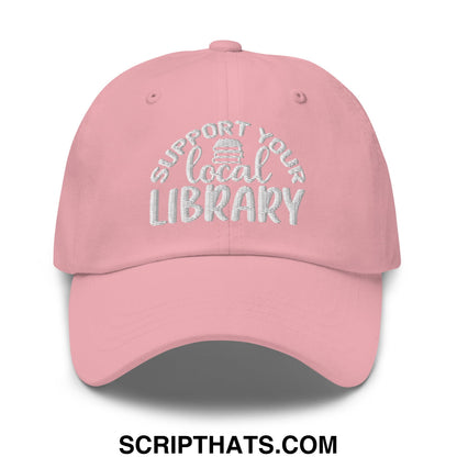 A soft pink embroidered unstructured dad hat with white support your local library text and a stack of books icon