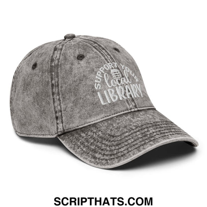 A faded gray unstructured denim dad hat embroidered with white support your local library text and a small book icon