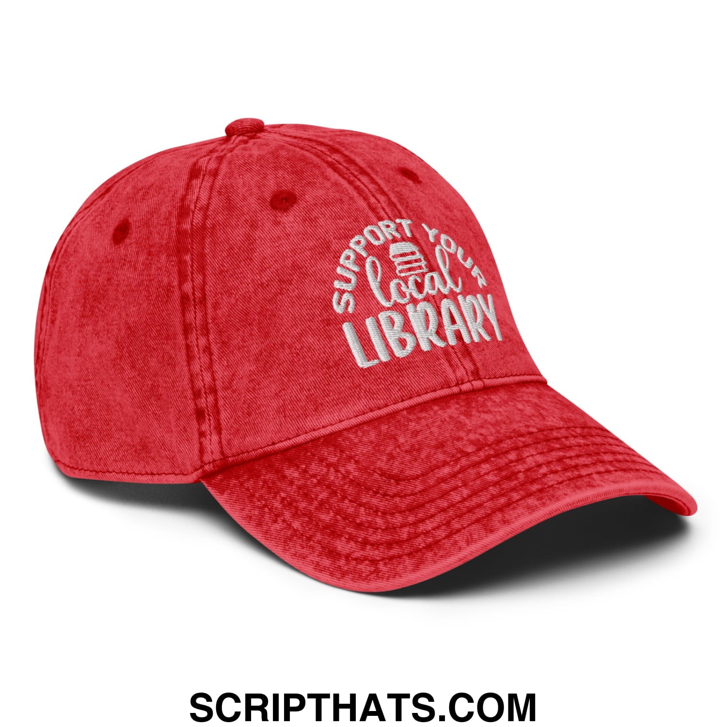 A red distressed denim dad hat embroidered with support your local library text and a small book icon