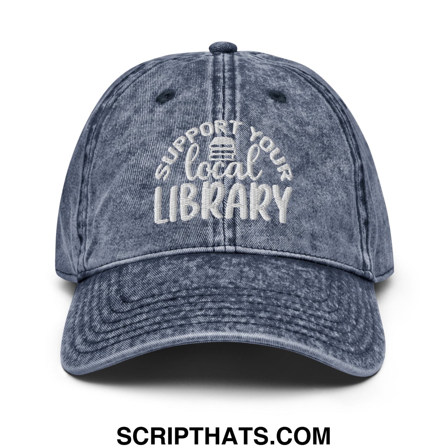 A faded blue denim dad hat with white embroidered support your local library text and a small library icon