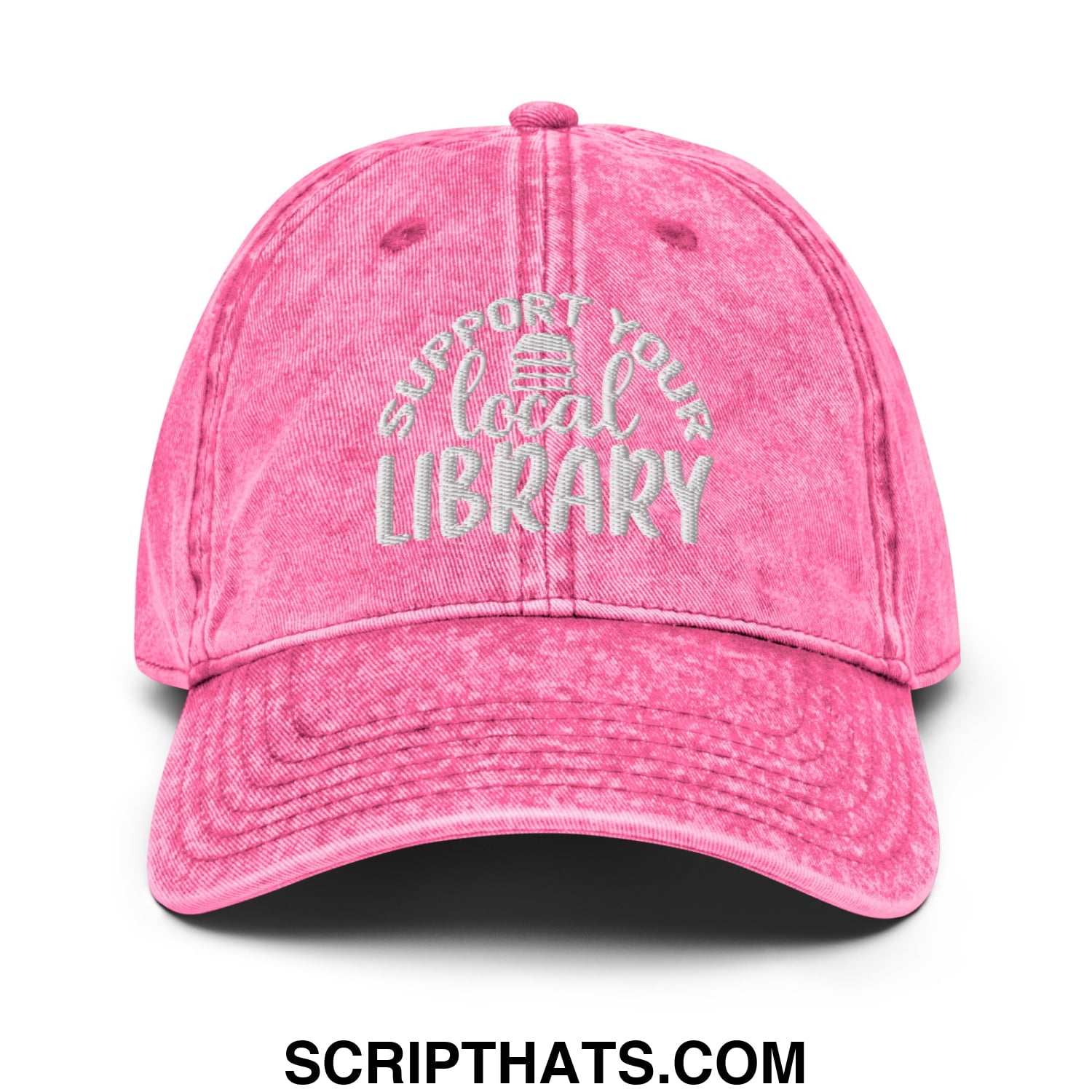 A faded pink denim dad hat with white embroidered support your local library text and a small library icon