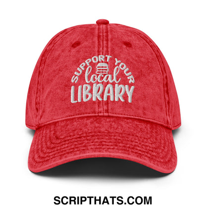 Red distressed cotton dad hat with white embroidered support your local library text and small book icon above local