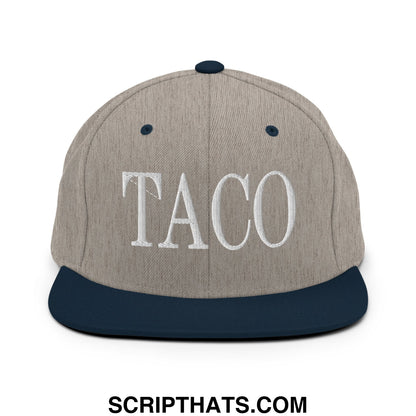 A gray and navy blue snapback hat with taco embroidered in white thread on the flat bill brim