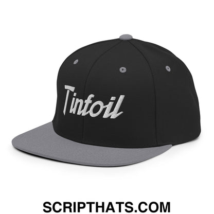 Black snapback hat with gray flat bill brim and silver foiled tinfoil logo embroidered on the front