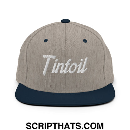 A heather gray snapback hat with a navy blue flat bill and white tinfoil sports script embroidery