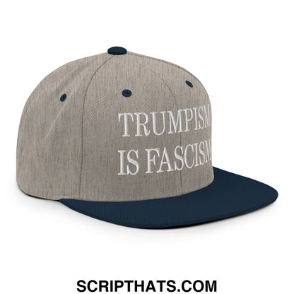 A gray and navy blue snapback hat with white embroidered text reading trumpism is fascism on the front panel