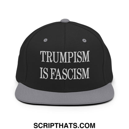 Black snapback cap with gray brim and white embroidered trumpism is fascism text in classic serif font