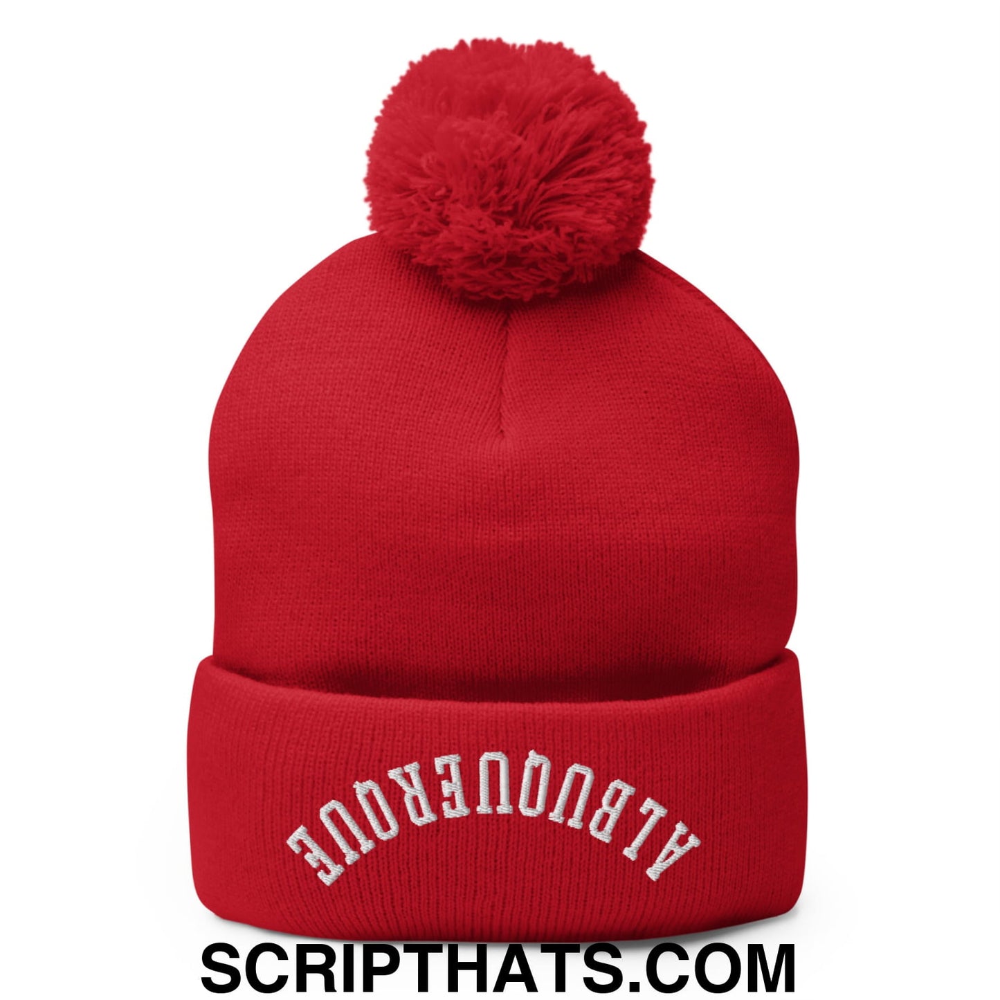 Red knit beanie with fluffy pom pom and white embroidered albuquerque text on cuff for cold weather use
