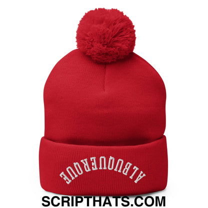 Red knit beanie with fluffy pom pom and white embroidered albuquerque text on cuff for cold weather use