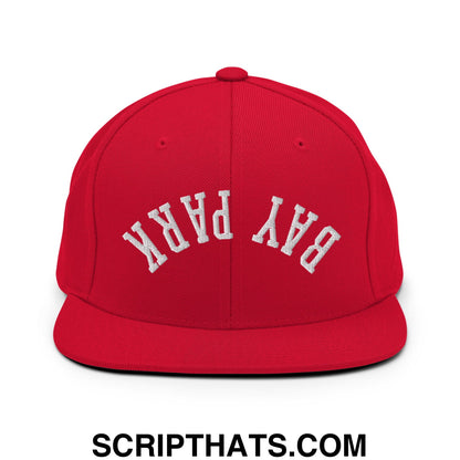 Red snapback cap with white embroidered bay park lettering and flat bill brim in a streetwear style design