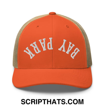 Orange trucker hat with beige mesh back and white embroidered bay park text on front in upside down style