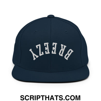 Navy blue snapback cap with white arched breezy embroidery featuring a flat bill brim and adjustable back closure