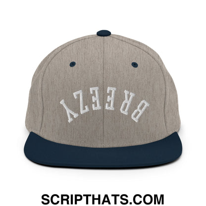 A gray and navy blue snapback hat with white breezy embroidery on the front and a flat bill brim