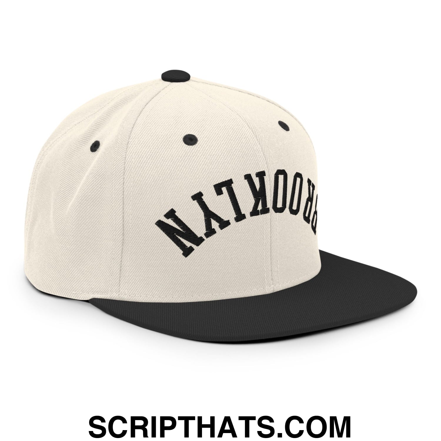 Cream-colored snapback cap with black flat bill brim and embroidered brooklyn in bold arching letters
