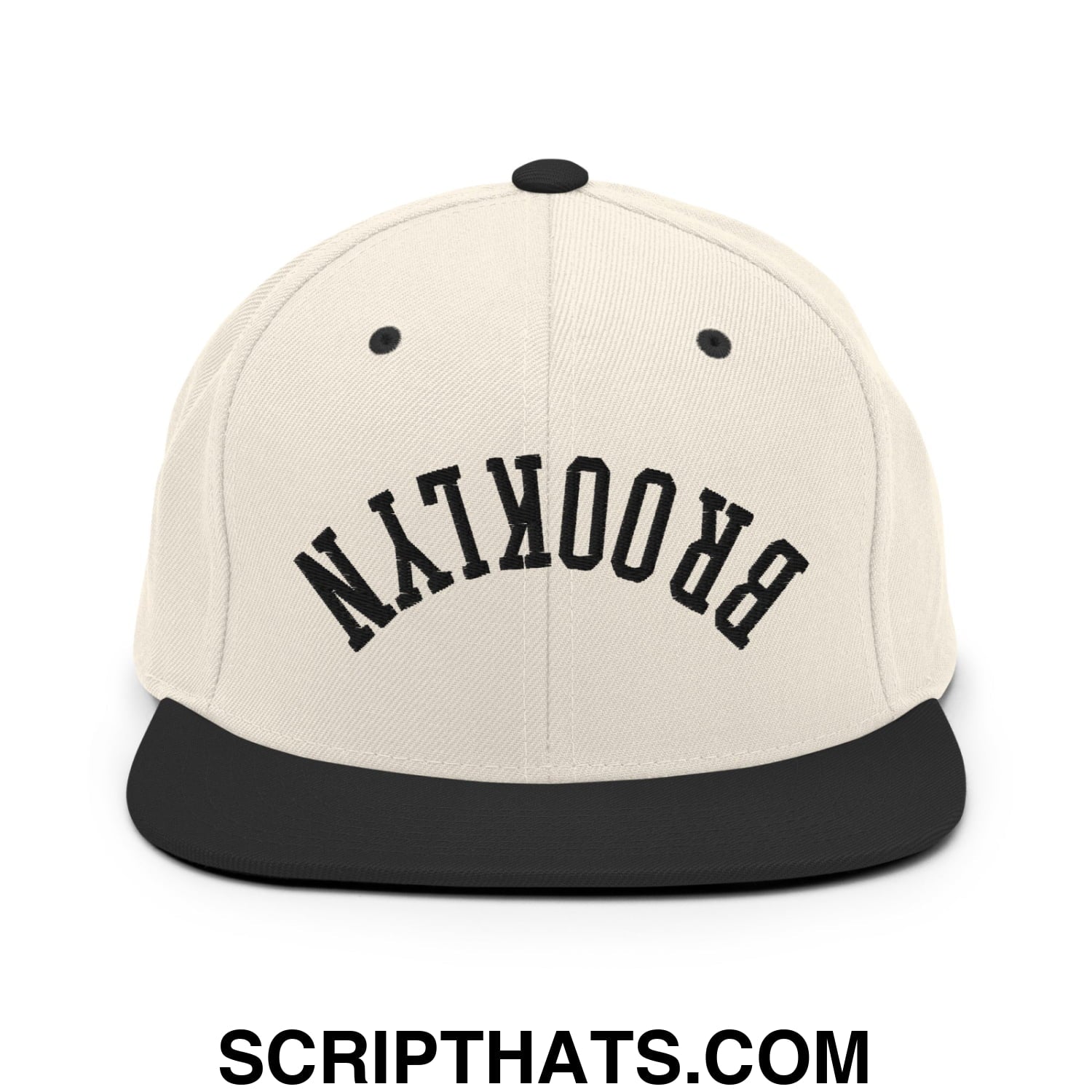 Beige snapback cap with black flat bill brim and upside down brooklyn embroidered in bold arching letters