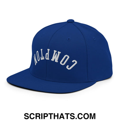 Royal blue snapback hat with white embroidered compton arched lettering and flat bill brim for casual wear