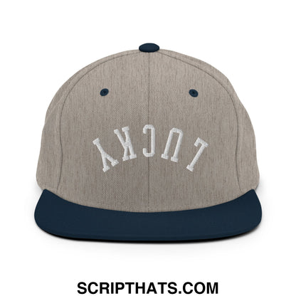 A heather gray snapback hat with navy blue brim and lucky embroidered in white on the front flat bill brim
