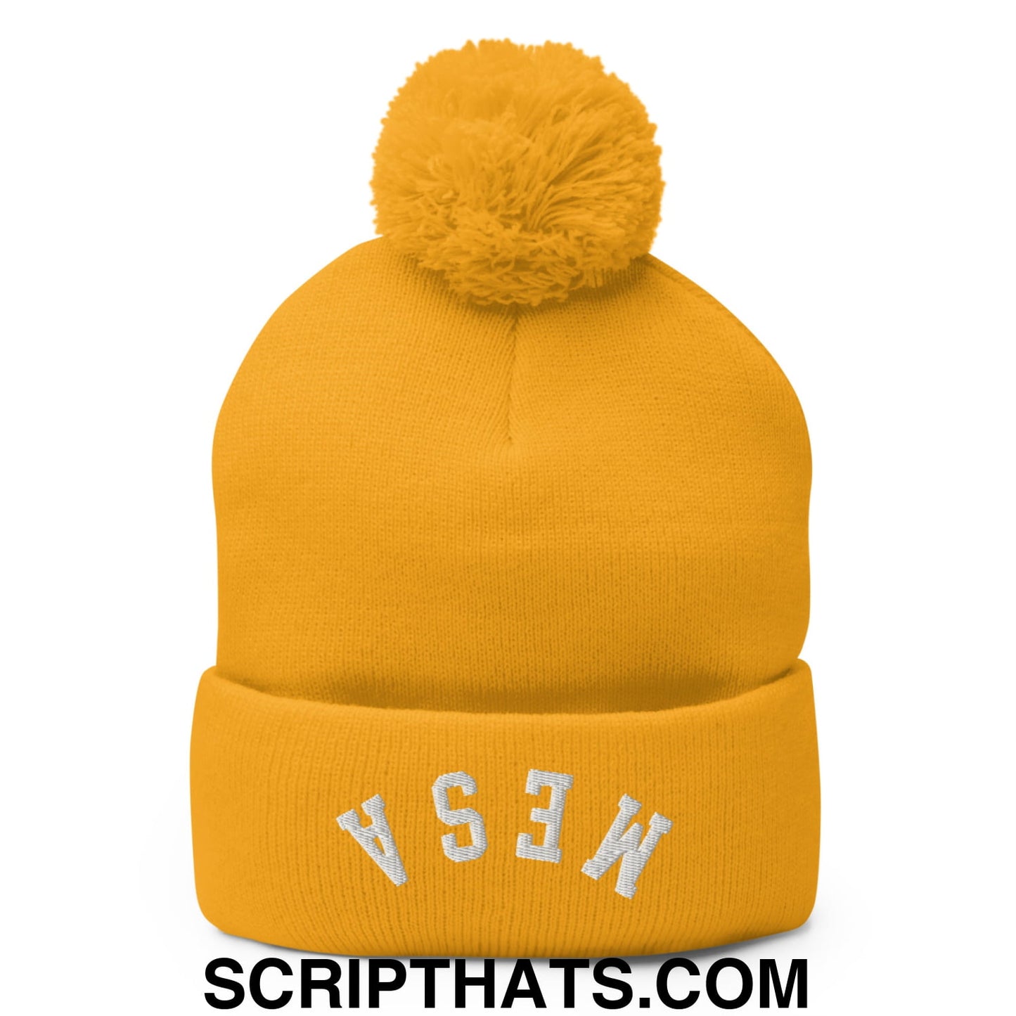 A mustard yellow knit beanie with a fluffy pom pom and white embroidered lettering on the cuff