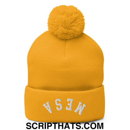 A mustard yellow knit beanie with a fluffy pom pom and white embroidered lettering on the cuff