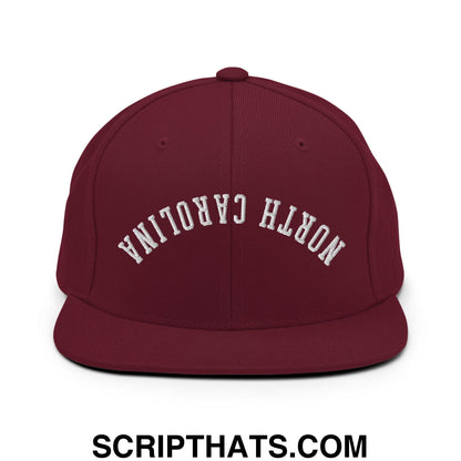 Maroon snapback hat with white embroidered north carolina text in an arched design and flat bill brim