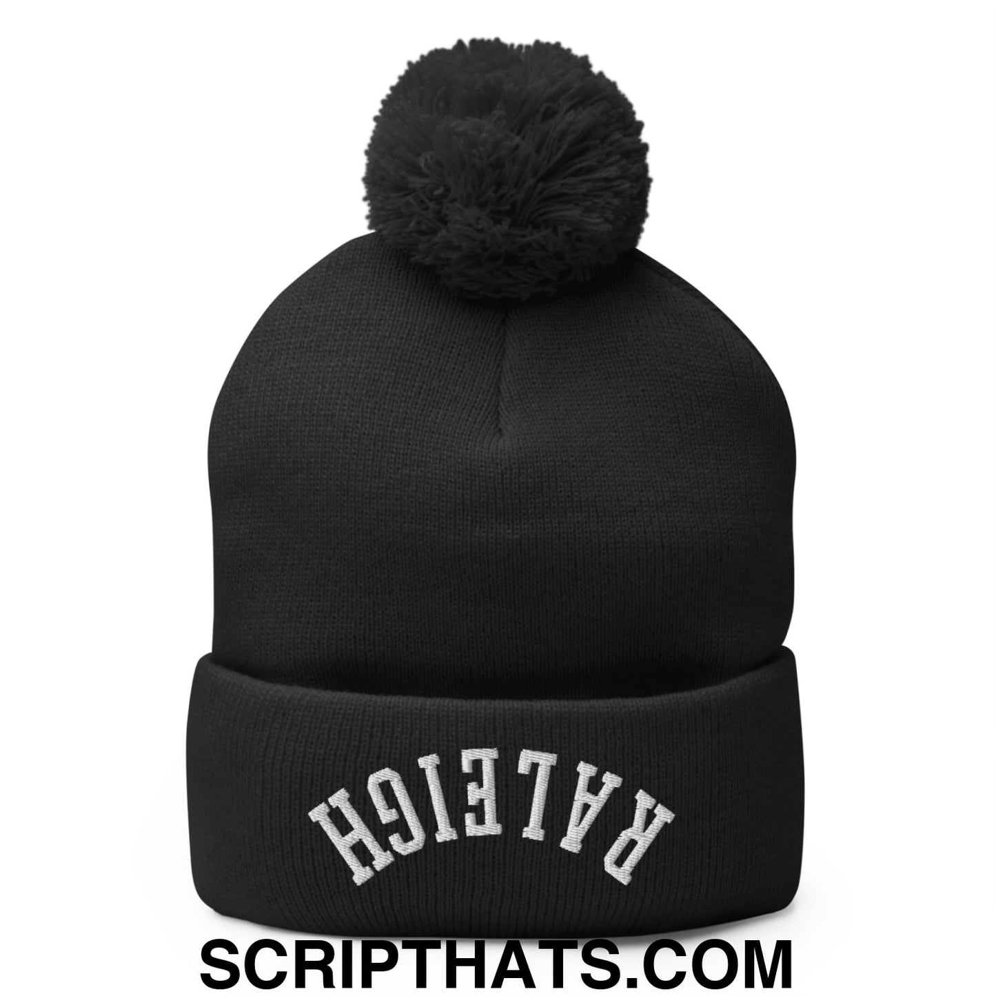 Black knit beanie with fluffy pom pom and white embroidered upside down raliegh lettering in an arched design
