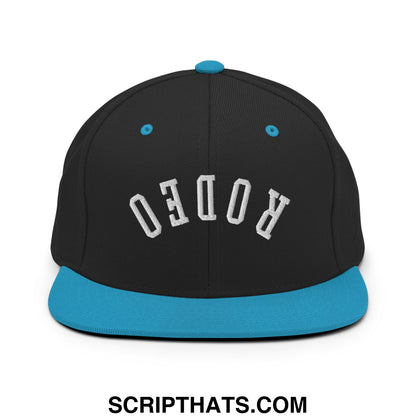 Black snapback cap with teal brim and button featuring white rodeo embroidery on front, flat bill brim style