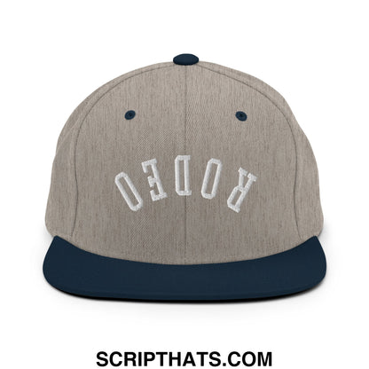 A gray and navy blue snapback hat with upside down rodeo embroidered in white on a flat bill brim