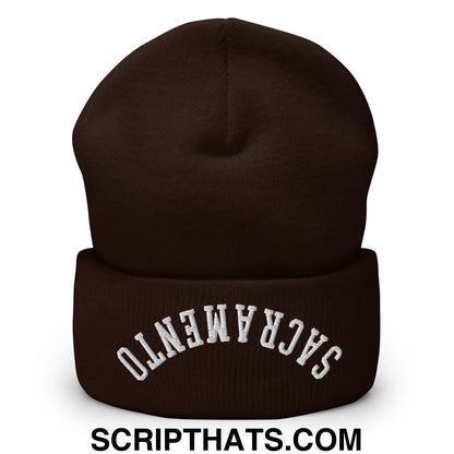 A dark brown knit beanie with white upside down sacramento embroidered on the folded cuff