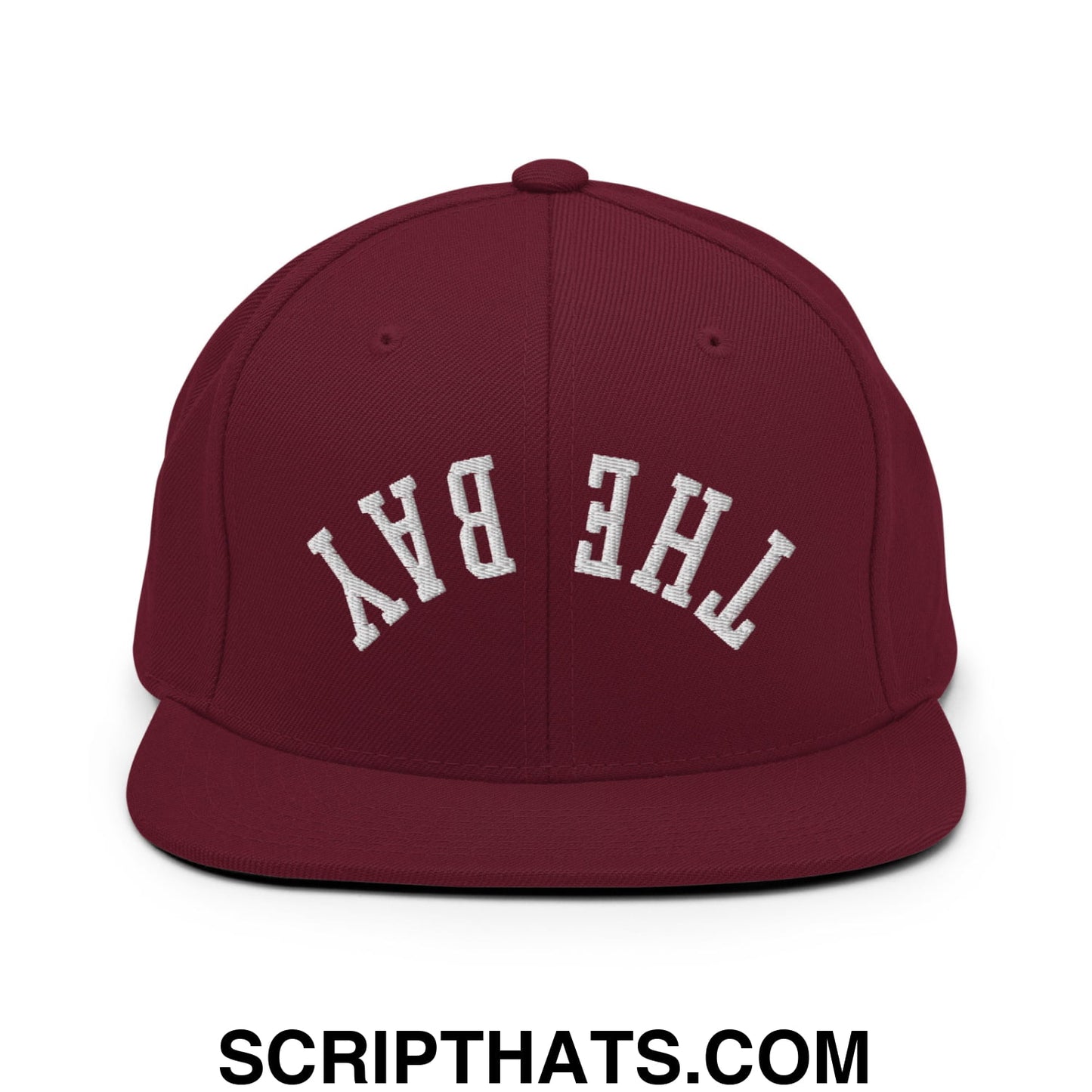 Maroon snapback cap with white embroidered the bay lettering and flat bill brim in upside down design