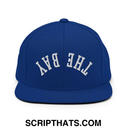 Royal blue snapback hat with white embroidered the bay lettering and flat bill brim in classic arched design