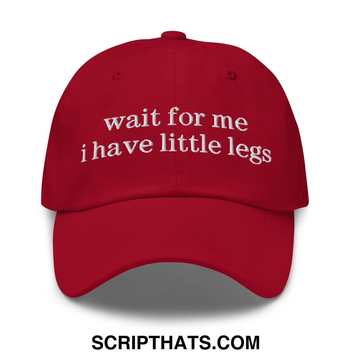 A vibrant red unstructured dad hat with white embroidered wait for me i have little legs text